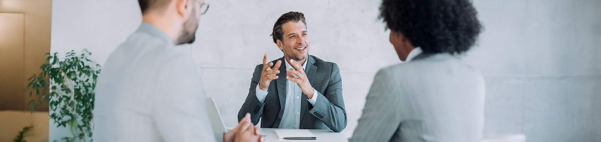 Eine Person erläutert etwas im Gespräch mit zwei weiteren Personen in einem Büro.
