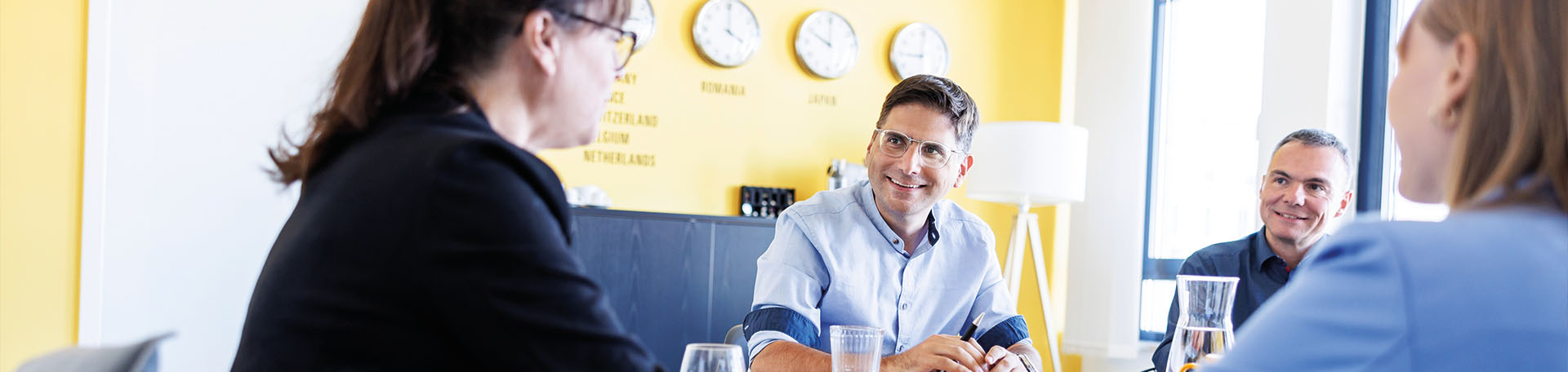 Several employees are sitting together in a meeting room and having a conversation at a table.
